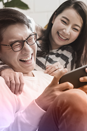 Two people laughing while looking at their mobile device